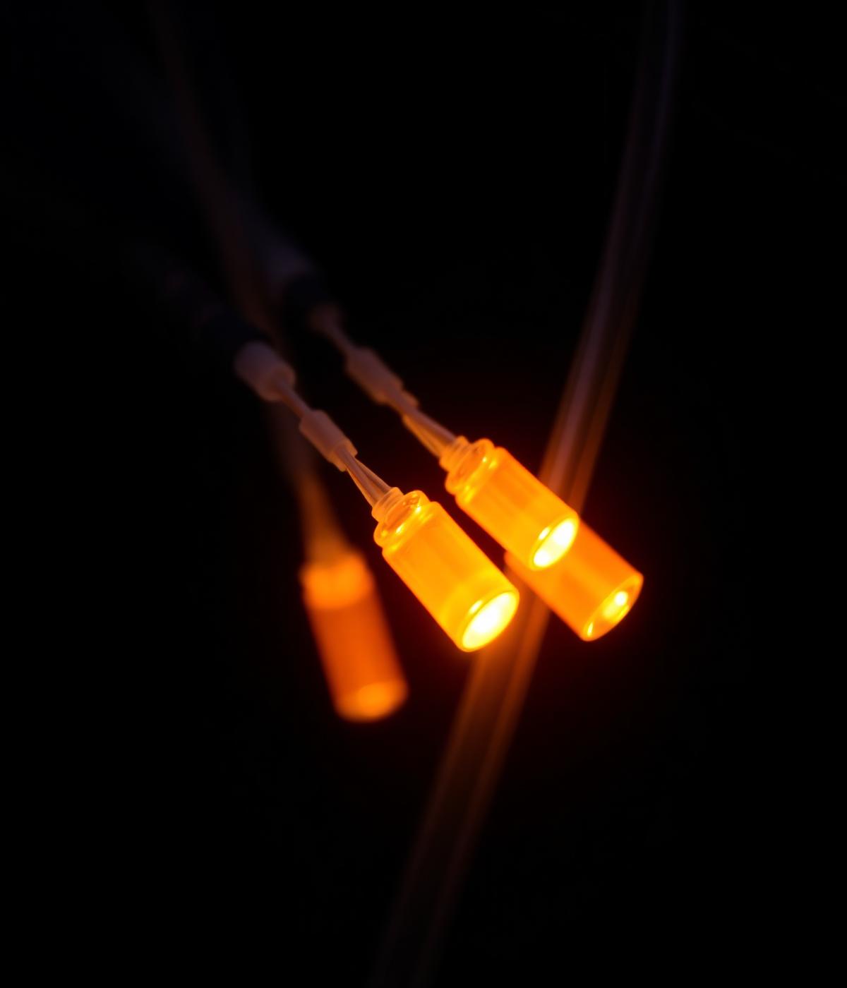 Macro photograph of amber illuminated fiber optic cables against a dark background